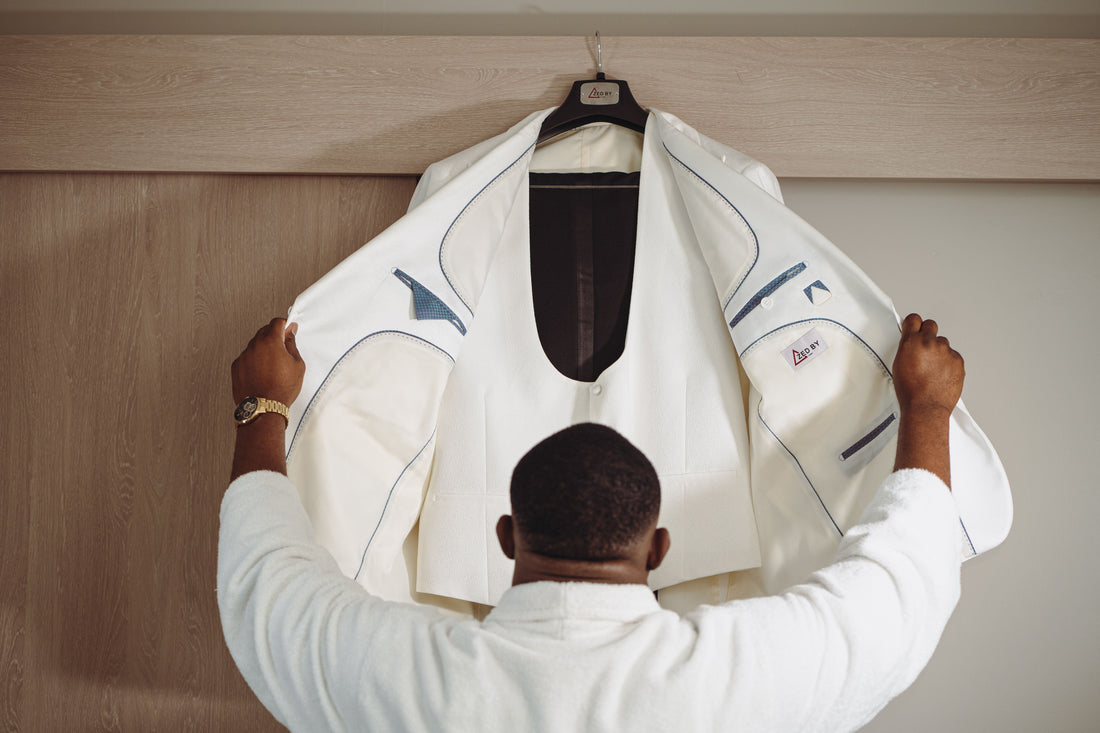 Interior details of a custom tailored white menswear tuxedo jacket with fine blue canvas stitching and signature brand label.