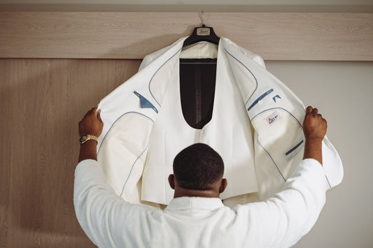 Interior details of a custom tailored white menswear tuxedo jacket with fine blue canvas stitching and signature brand label.