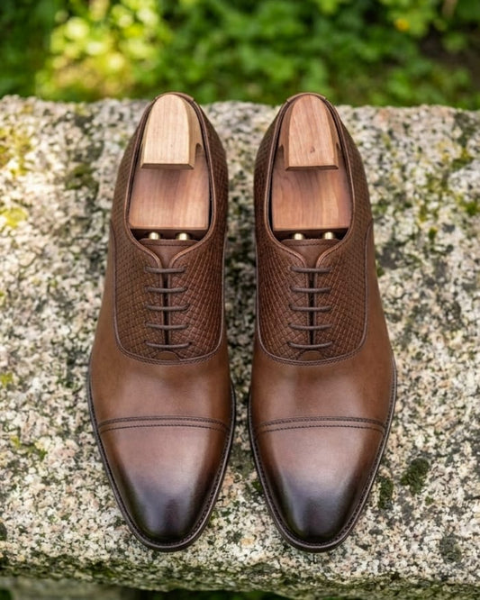 Pair of brown leather shoes with red bottoms